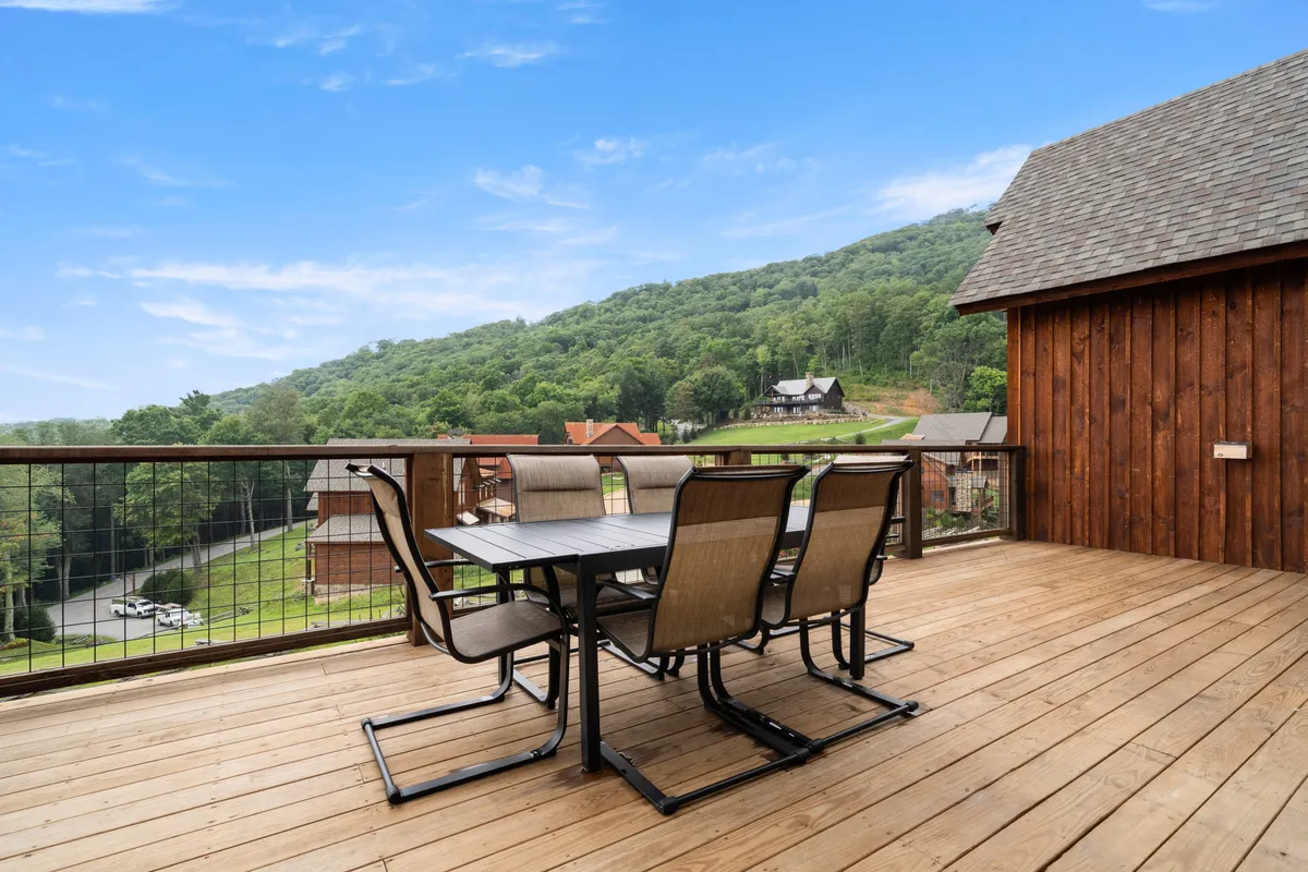 An inviting exterior deck setup with a dining table and chairs, surrounded by cabins and overlooking majestic mountain vistas. The scene evokes a sense of tranquility and connection with nature, perfect for al fresco meals, sunrise coffees, or evening relaxation under the stars.