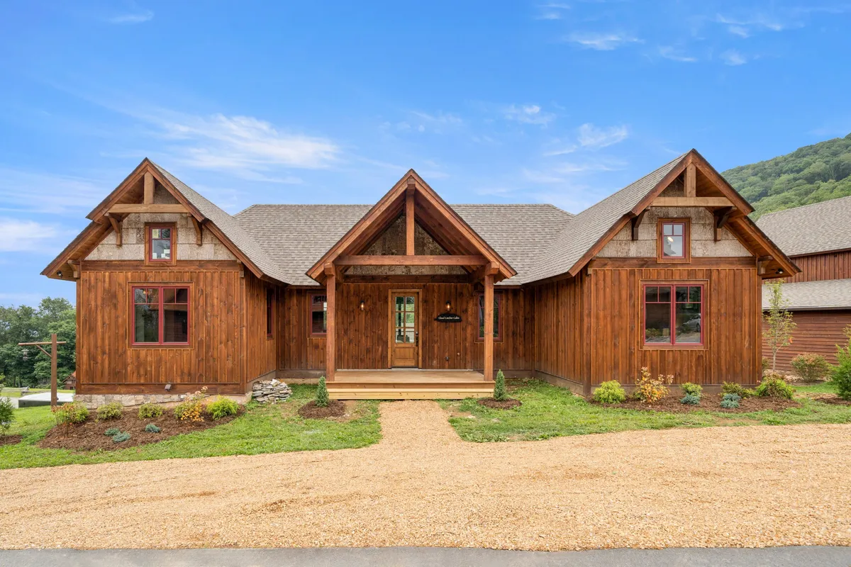 This exterior shot captures the front porch of the home, showcasing its inviting wooden facade, beautifully landscaped garden, and ample space for gatherings. The warm evening light hints at memorable sunset moments and outdoor relaxation possibilities.