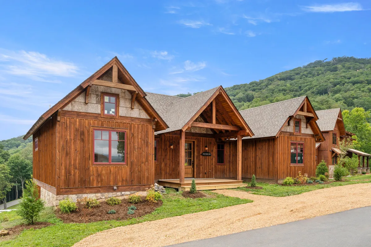 An inviting view of the home’s wooden exterior, spacious front porch, and well-maintained landscaping, set against a stunning mountain backdrop. The porch is perfect for relaxing or gathering with friends and family, highlighting both comfort and connection to the outdoors.