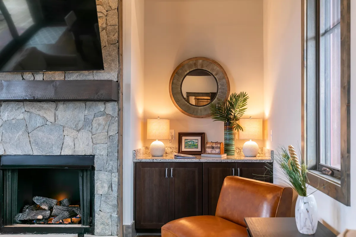 This inviting living area features a glowing fireplace, a comfortable seating arrangement, decorative plants, and stylish lighting. The ambiance is warm and perfect for post-adventure relaxation—ideal for snuggling up, sharing stories, or sipping cocoa after a day on the slopes.