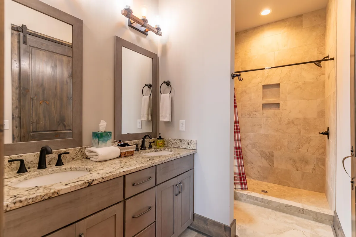 A modern double sink vanity with large mirrors and a glass-enclosed shower area. The space is bathed in soft, natural light, suggesting a refreshing, spa-like atmosphere perfect for personal care routines.